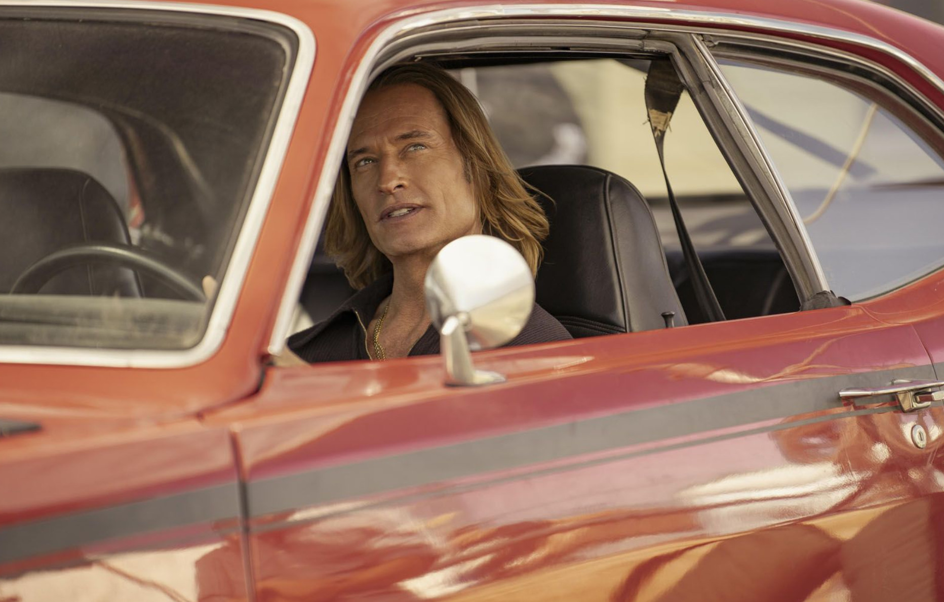 Josh Holloway dans une voiture rouge dans la série Duster.